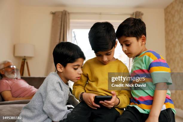 three young boys playing on a smart phone together - the internet stock pictures, royalty-free photos & images