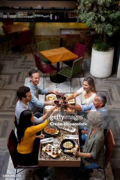 group of friends eating at a restaurant and making a toast - dining experience stock pictures, royalty-free photos & images