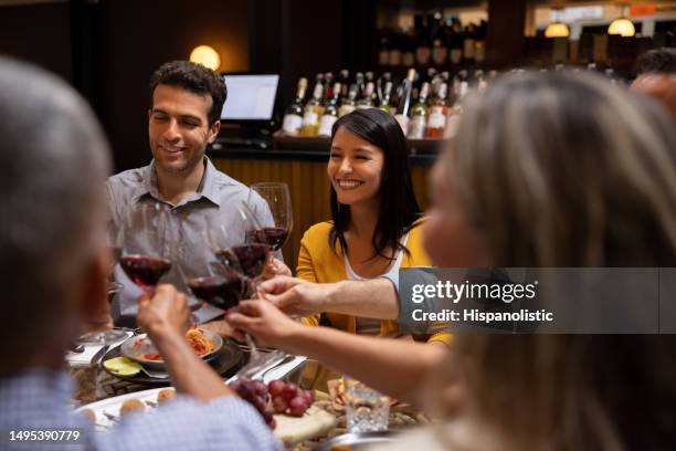 happy group of friends at a restaurant making a toast - wine enjoyment stock pictures, royalty-free photos & images