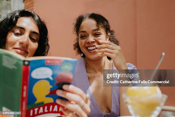 two woman read and discuss a italian language book on a terrace - turismo esperienziale foto e immagini stock