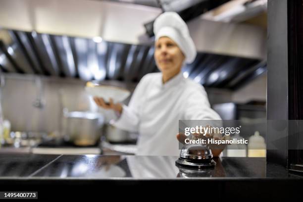 chef con comida lista para comer tocando una campana en un restaurante - resonar fotografías e imágenes de stock