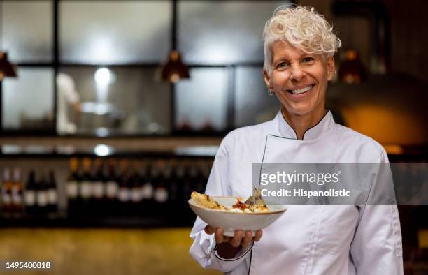 happy chef holding a plate at a fine dining restaurant - chef vs chef stock pictures, royalty-free photos & images