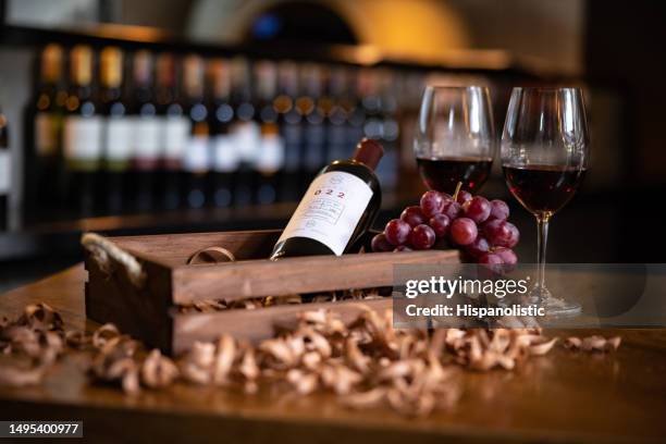 bicchieri di vino rosso accanto a una bottiglia in una cantina - wine bar foto e immagini stock