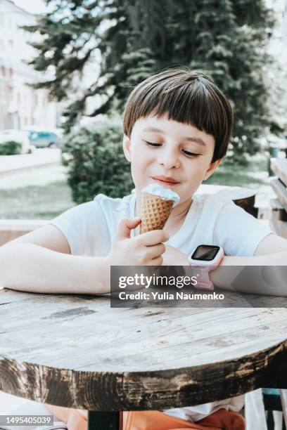 a little girl eats ice cream outside on a hot day. - scorching start to the school summer holidays stock-fotos und bilder