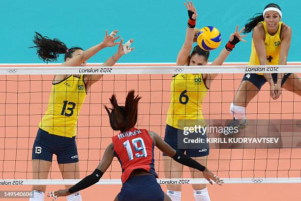 Destinee Hooker spikes as Brazil's Sheilla Castro and Thaisa Menezes attempt to block during the women's preliminary pool B volleyball match between...