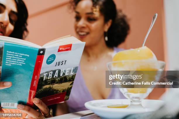 two woman read and discuss a travel book on a terrace, whilst on vacation in italy. - intelligence agency stock pictures, royalty-free photos & images