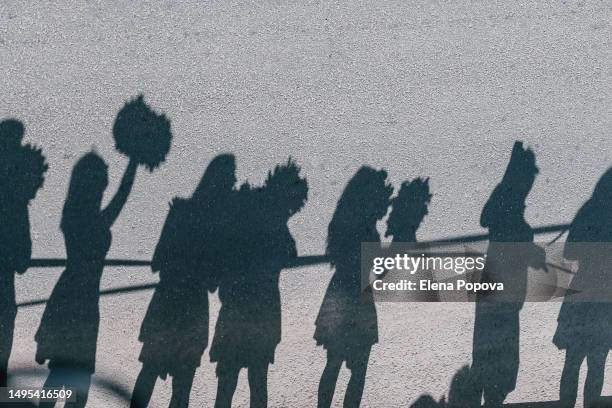 silhouettes group of female fans greeting amateur triathletes and dancing with pom pom. full frame, abstract background, focused on dark shadows - black cheerleaders - fotografias e filmes do acervo