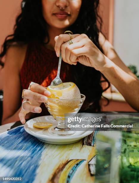 a woman enjoys a refreshing lemon sorbet, served in a frozen lemon - positano stockfoto's en -beelden