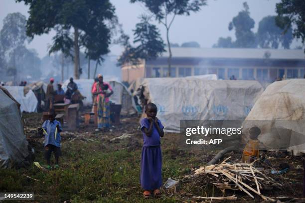 Displaced Congolese girl stands next to a bundle of firewood in a camp set-up in Kanyarucinya village in Kibati district on the outskirts of Goma,...