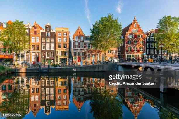 old historic dutch houses reflecting in the canal on a sunny day, amsterdam, netherlands - amsterdam blue sky stock-fotos und bilder