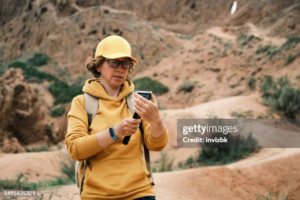 female tourist is streaming in canyon. medium shot - desert sable stockfoto's en -beelden
