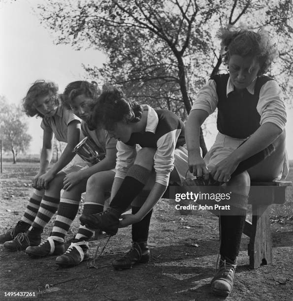 Two members of Maldon Ladies' Football Club watching two members of their opposing team, Halstead Ladies FC, putting on their boots before a match,...