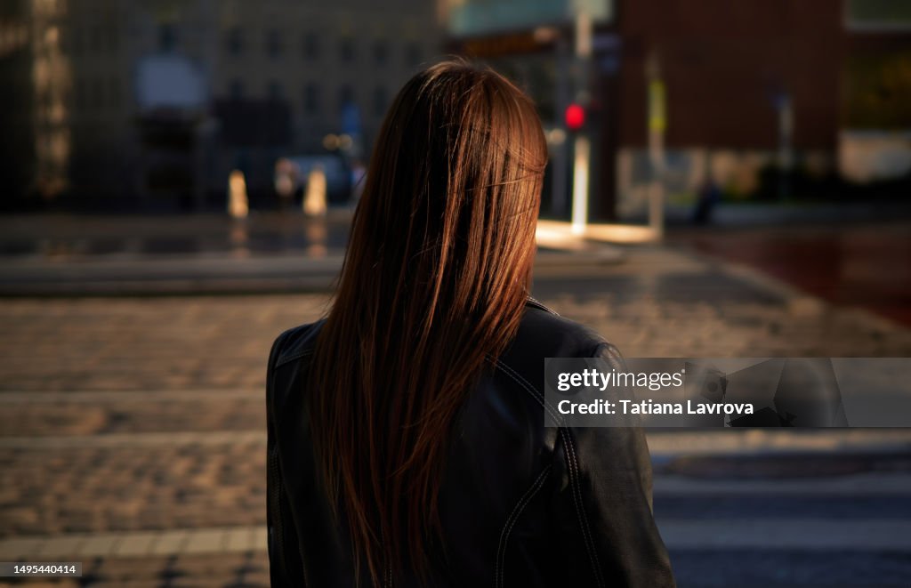 Lonely woman standing on the street with her back to the camera. Depression, mental health, stress, illness, sadness, emotional abuse concept