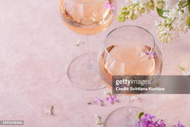 two glasses of rose wine and lilac flowers - wine glasses stock pictures, royalty-free photos & images