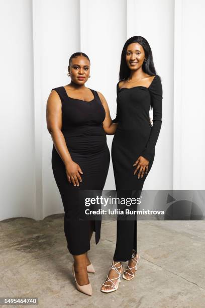 two beautiful women of african ethnicity in long fitting black dresses standing side by side - form fitted stock pictures, royalty-free photos & images