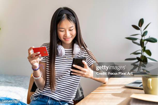 asian young woman shopping online using smartphone. young woman activating her first credit card via mobile. - credit card art stock pictures, royalty-free photos & images