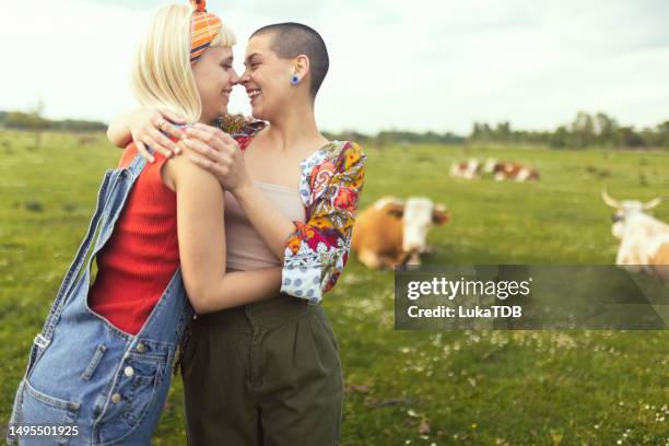 two women in love kiss while spending the day in a pasture surrounded by domestic animals - photos of lesbians kissing stock pictures, royalty-free photos & images