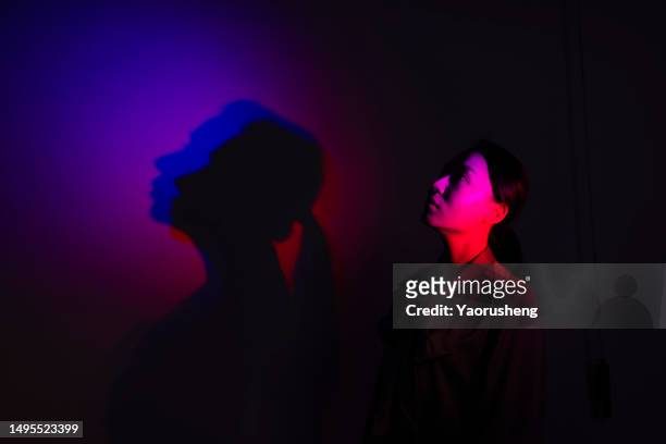 hopeful woman in neon light - dark room stock-fotos und bilder