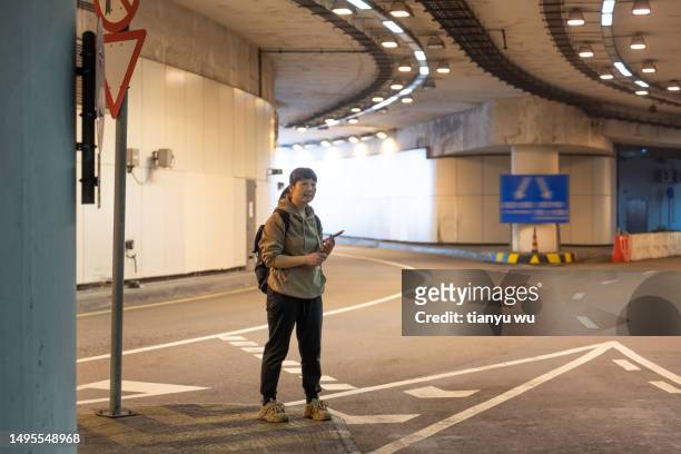 a female tourist is waiting for a taxi at an underground station in the city - air taxi stock pictures, royalty-free photos & images