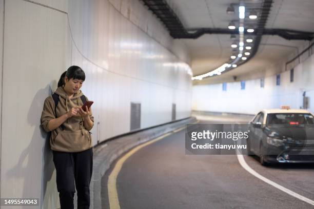 a female tourist is waiting for a bus at an underground bus stop in the city - air taxi stock pictures, royalty-free photos & images
