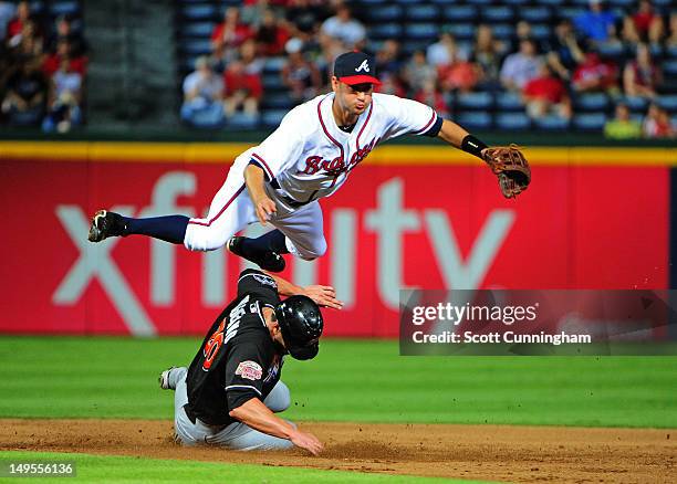 Paul Janish of the Atlanta Braves turns a double play against Justin Ruggiano of tthe Miami Marlins at Turner Field on July 30, 2012 in Atlanta,...