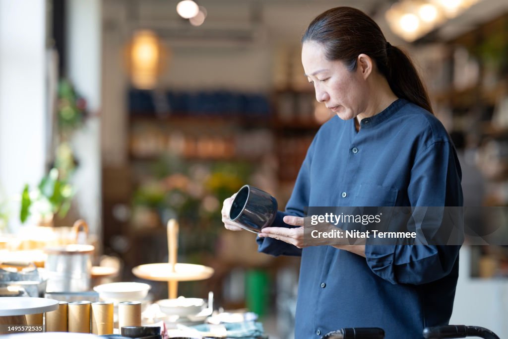 Personalize Your Customer Experience with an E-co-friendly Product to Increase Your Sales Funnel. Side view of a Japanese customer deciding on a product made from recycled material at a retail display during shopping for home decor products.