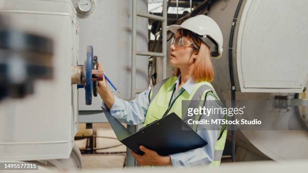 young asian female industrial engineer in hard hats checking steam boiler in chemical manufacturing factory. heavy industry and engineers. - furnace & duct stock pictures, royalty-free photos & images