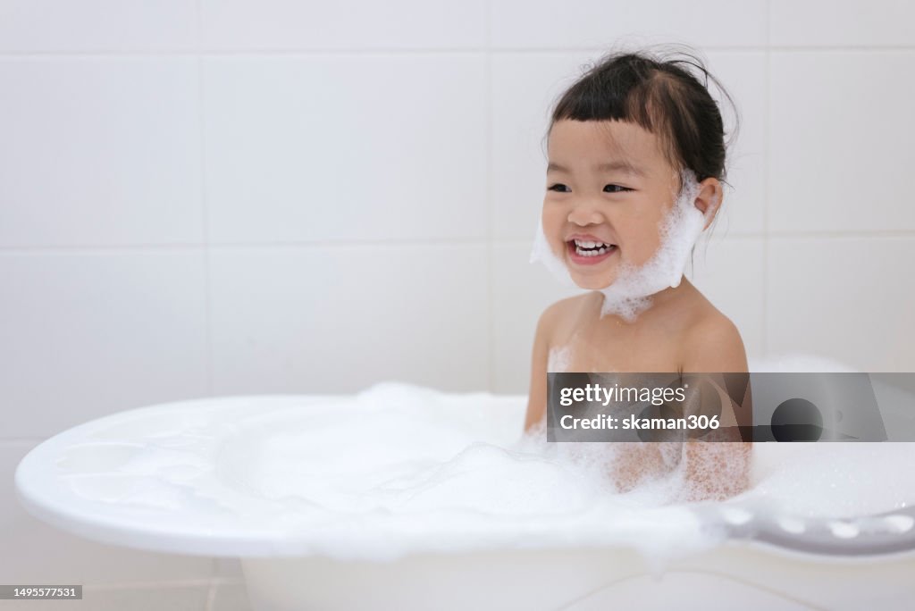 Positive emotion Asian baby girls enjoy showering and playing foam and soap sud in bathroom copy space
