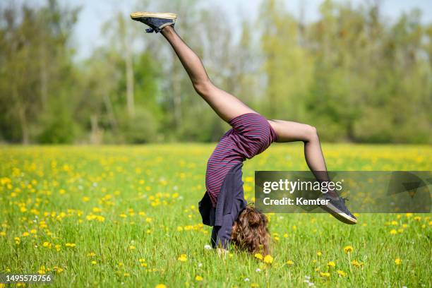 adolescente haciendo parada de manos al aire libre - girl in dress doing handstand fotografías e imágenes de stock