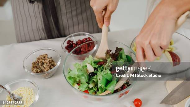 closeup of young asian women friends preparing vegetarian and cooking salad in kitchen table at home. lifestyle healthy food eating enjoying natural life and plant-based diet. - salad tossing stock pictures, royalty-free photos & images