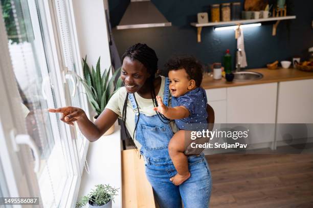 mother and baby son looking through window from their home - baby pointing stock pictures, royalty-free photos & images