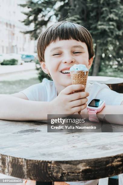 a little girl eats ice cream outside on a hot day. - scorching start to the school summer holidays stock pictures, royalty-free photos & images