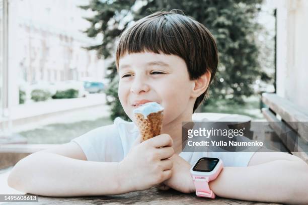a little girl eats ice cream outside on a hot day. - scorching start to the school summer holidays stock-fotos und bilder