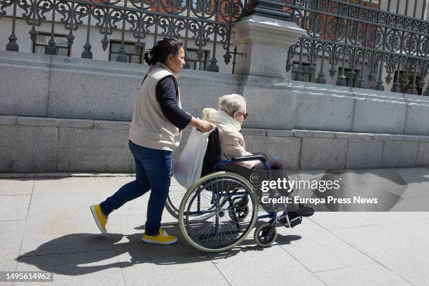 An elderly woman in a wheelchair and her caregiver stroll through the city center on June 4 in Madrid, Spain. The population over the age of 64 in...