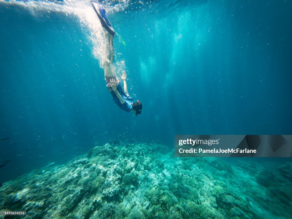 Young Man Snorkeling and Diving Downwards To Coral Reef