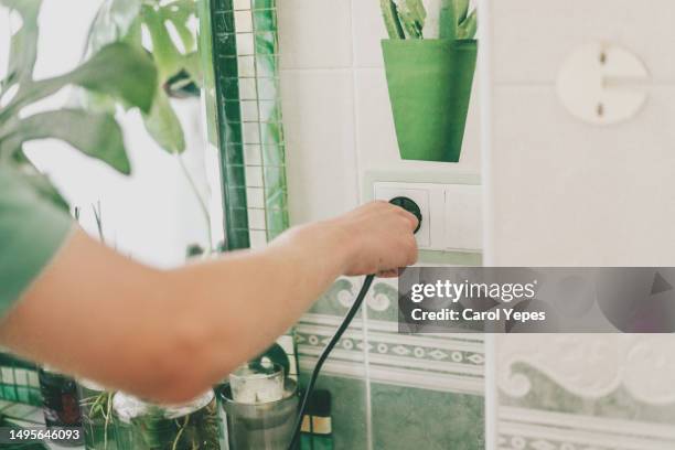 close up of people plug cable in to power source in the bathroom - eletrodoméstico imagens e fotografias de stock