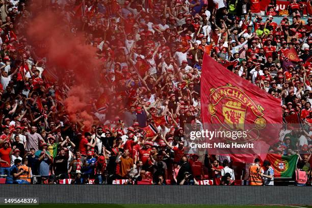 Manchester United flag is waved from the stands as a flare burns during the Emirates FA Cup Final between Manchester City and Manchester United at...