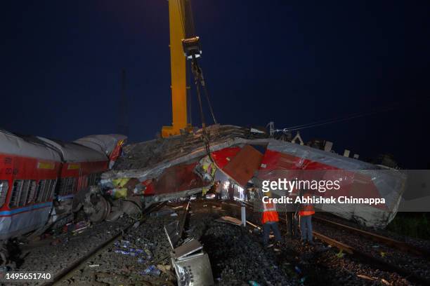 Crane removes the wreckage of a train from rail tracks on June 03, 2023 in Bahanaga village in Balasore district, India. Local media reports said...
