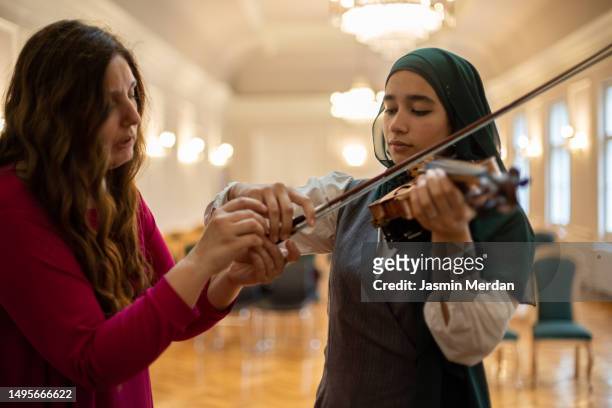 muslim female learning violin in music school - arab child stock pictures, royalty-free photos & images