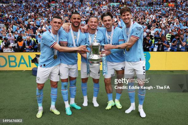 Phil Foden, Kyle Walker, Kalvin Phillips, Jack Grealish and John Stones of Manchester City hold the FA Cup Trophy after the team's victory in the...