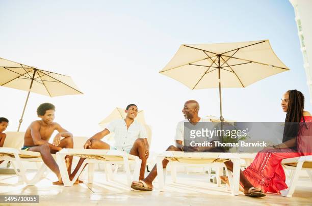 wide shot of smiling family relaxing by pool at all inclusive resort - all inclusive holiday stock-fotos und bilder
