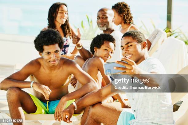 medium shot family taking a selfie by pool at all inclusive resort - teen boy shorts stock pictures, royalty-free photos & images