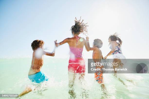 Wide shot siblings playing in waves in tropical ocean during vacation