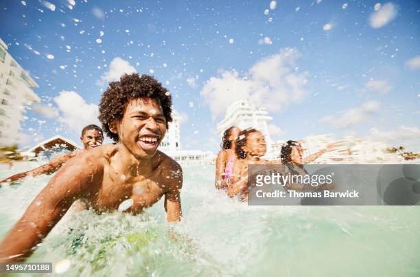 medium shot siblings playing in waves in  ocean during family vacation - quintana roo stock-fotos und bilder