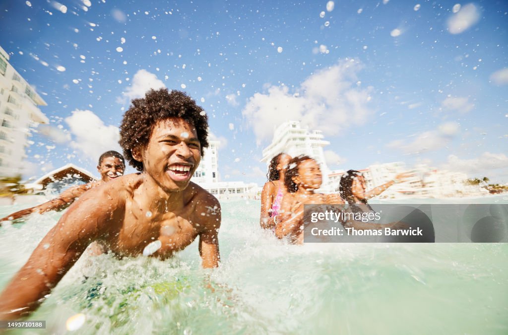 Medium shot siblings playing in waves in ocean during family vacation