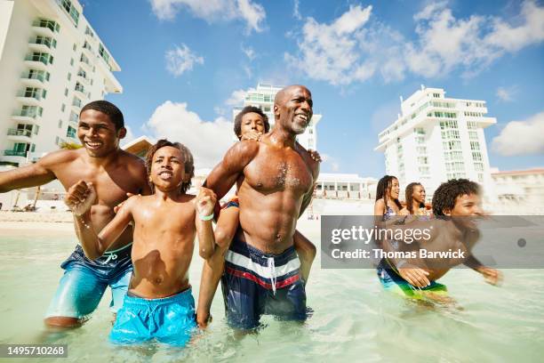 medium shot family playing in tropical ocean during family vacation - all inclusive holiday stock-fotos und bilder