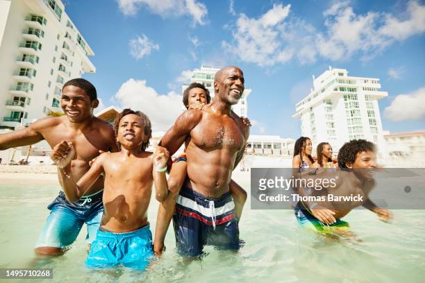 medium shot family playing in tropical ocean during family vacation - all inclusive holiday stock pictures, royalty-free photos & images