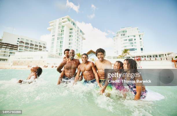 wide shot family playing in waves in  ocean during family vacation - all inclusive holiday stock pictures, royalty-free photos & images