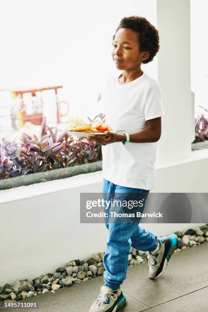 wide shot smiling boy carrying food from buffet at all inclusive resort - all inclusive holiday stock pictures, royalty-free photos & images