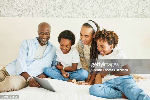 medium shot family watching movie on digital tablet in hotel room - all inclusive holiday stock pictures, royalty-free photos & images